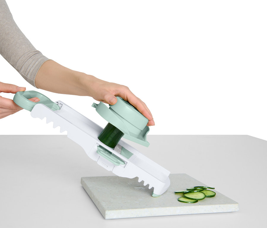 Žena krája uhorku pomocou krájača zeleniny s rúčkou a otočným nadstavcom.