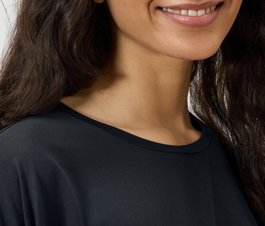 Detail tváre ženy s tmavými vlnitými vlasmi a čiernym tričkom.