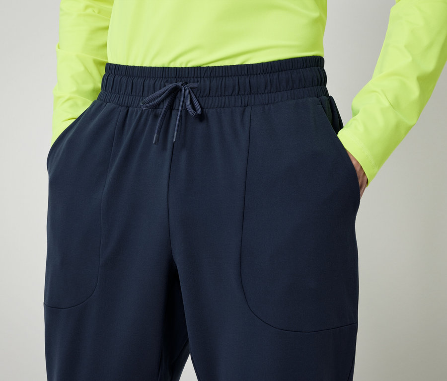 Osoba v neónovo zelenej košeli a tmavomodrých nohaviciach s rukami vo vreckách.