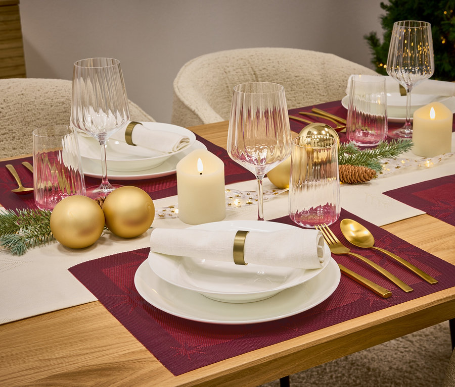 Prestretý stôl s vínnymi prestieraním, bielym riadom, pohármi, zlatými príbormi, sviečkami a ozdobami.
