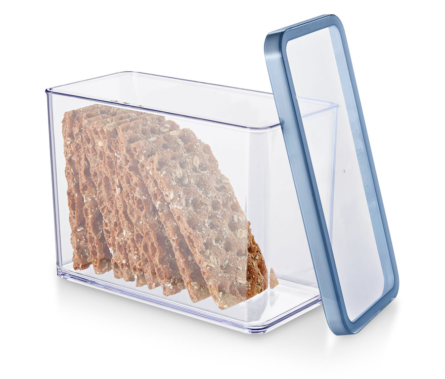 Priehľadná nádoba s modrým okrajom obsahuje balíček celozrnných krekrov.