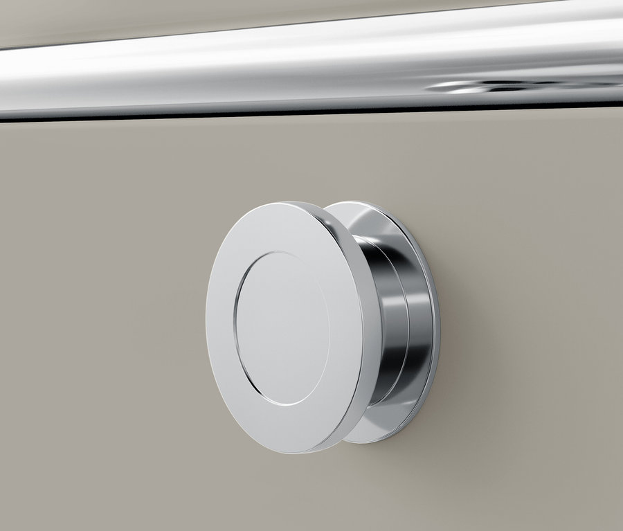 Detail chrómovej okrúhlej úchytky na béžovej zásuvke.