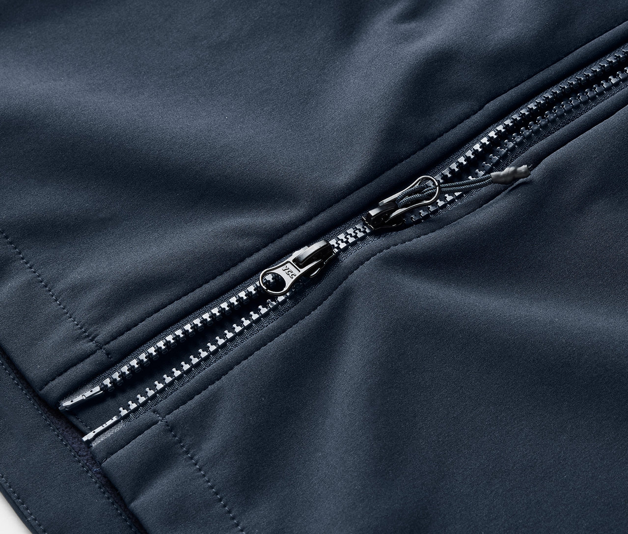 Detail softshellového kabáta v námorníckej modrej farbe so strieborným zipsom.