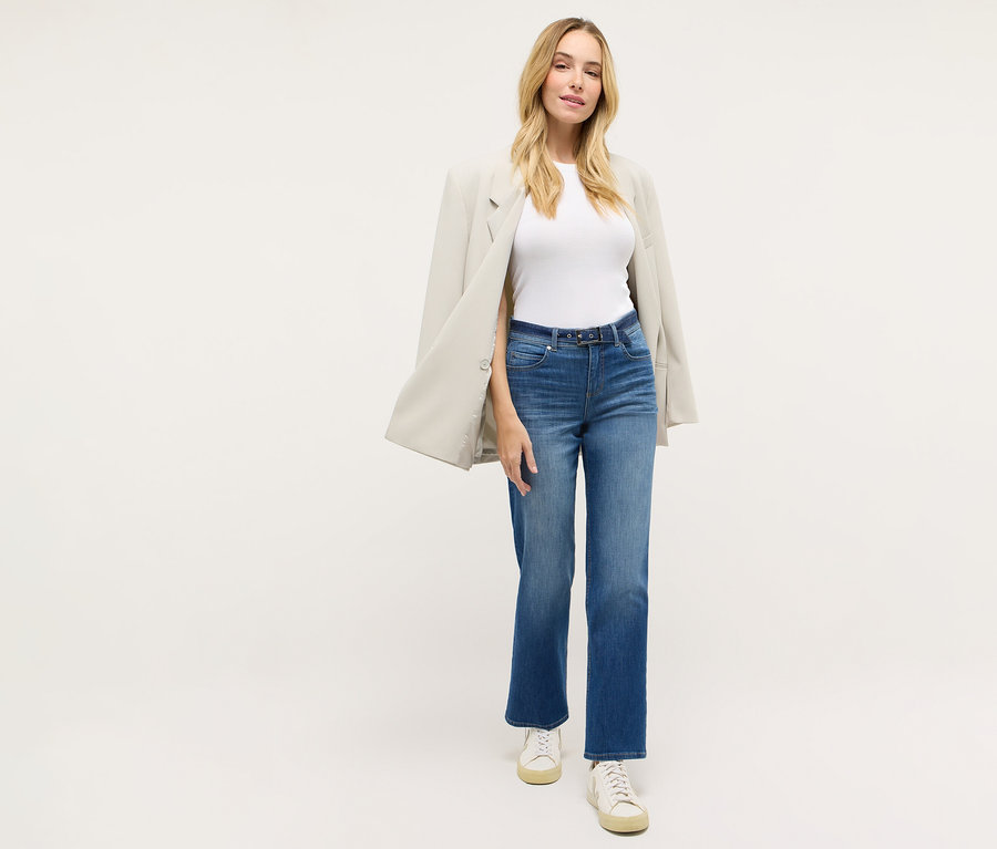 Žena má na sebe džínsy Angels »Lara City« Straight Fit, biele tričko, sako a tenisky.