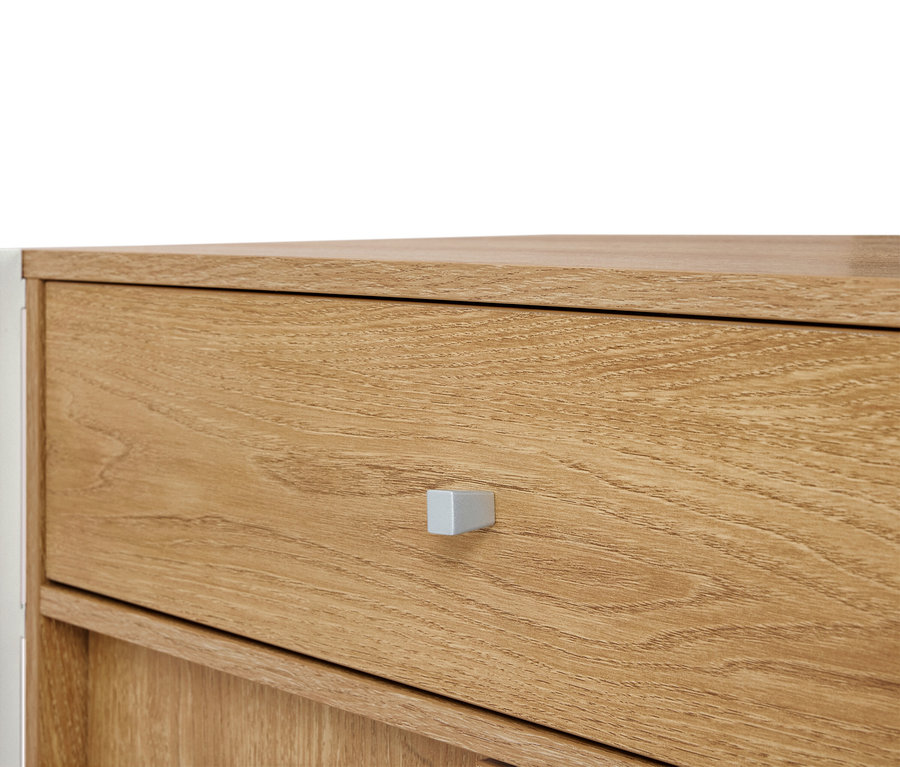Detailný záber na svetlohnedú drevenú komodu so striebornou rúčkou.