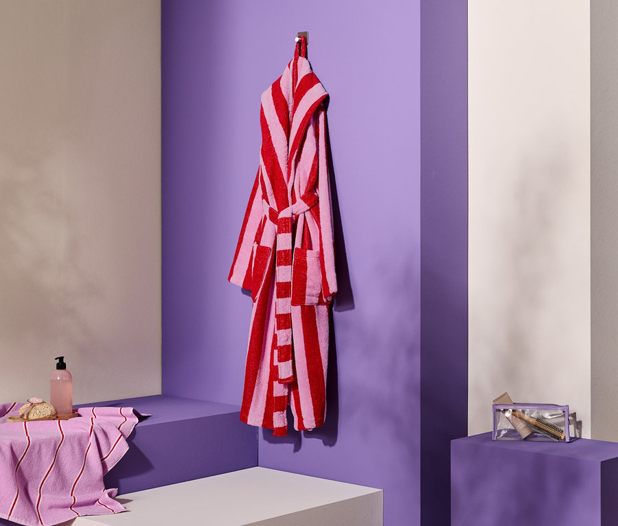 Prúžkovaný župan visí na háčiku vedľa uteráka, mydla a kozmetickej taštičky.