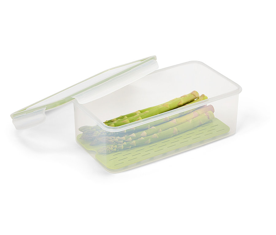 Niekoľko stoniek zelenej špargle leží v priehľadnej nádobe na potraviny so zelenou vložkou a priehľadným vekom.