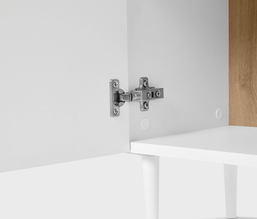 Detail skrine so strieborným pántom na bielych dverách.