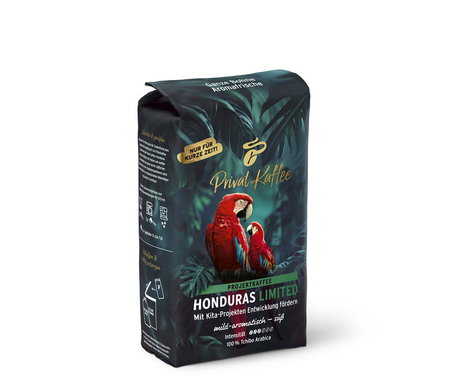 Tmavé balenie kávy Privat Kaffee Limited Edition Honduras s tropickými listami a dvoma červenými arami, nápis „Ganze Bohne“.