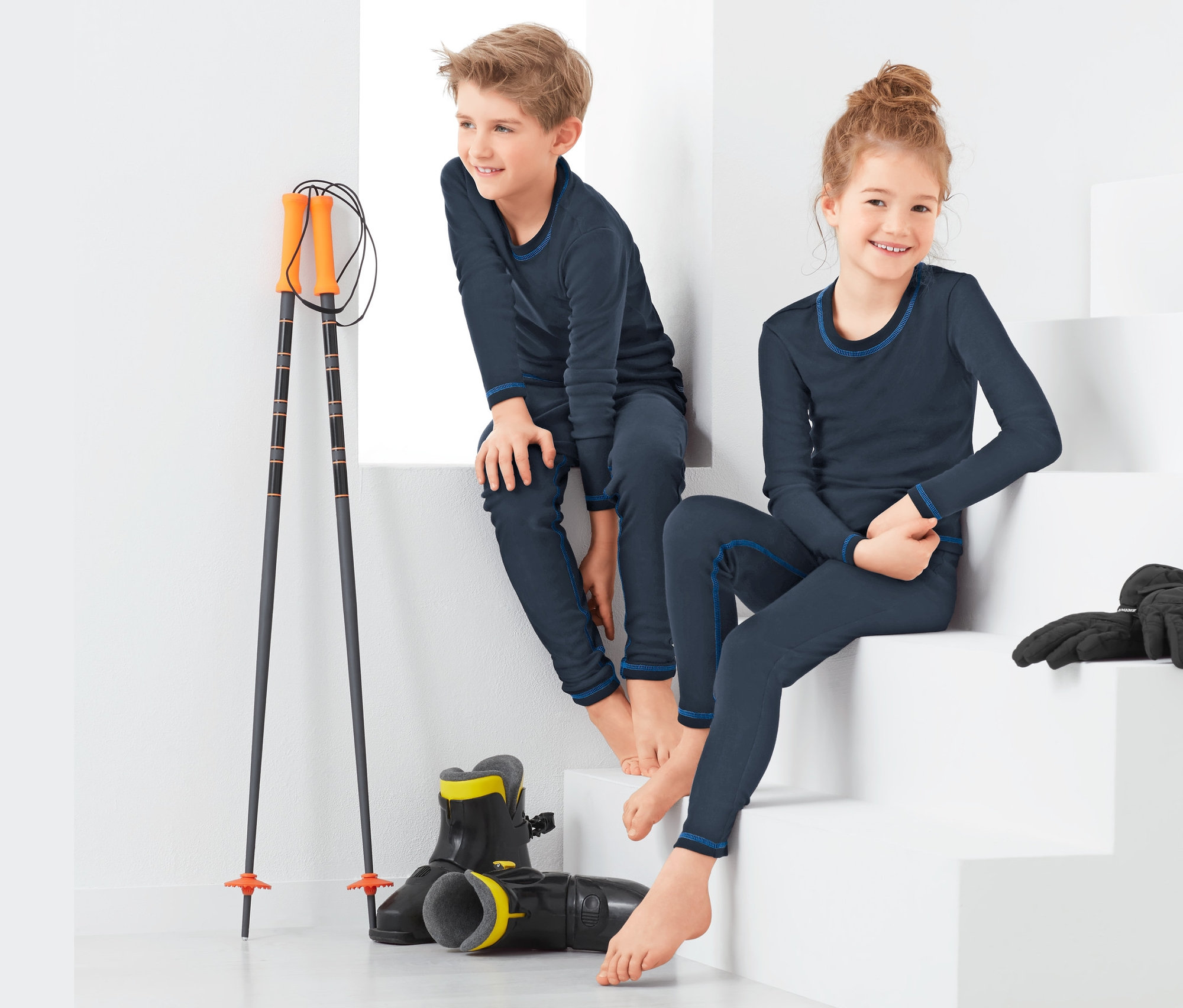 Chlapec a dievča sedia na bielych schodoch a majú na sebe funkčnú spodnú bielizeň.