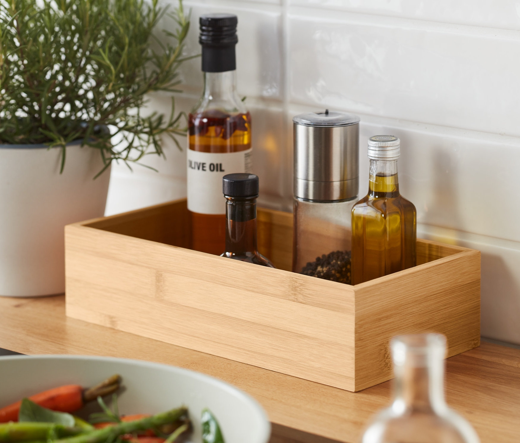 Bylinky v kvetináči a dva úložné boxy na korenie vedľa panvice so zeleninou.