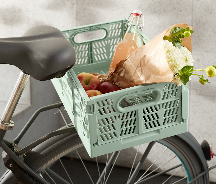 Skladacia debnička na mestský bicykel s jablkami, kvetmi a fľašou je umiestnená na bicykli.