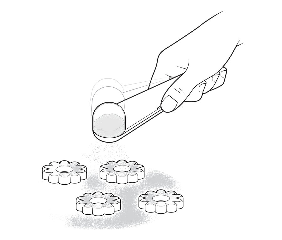 Ruka s pomôckou na sypanie práškového cukru posýpa sušienky práškovým cukrom.