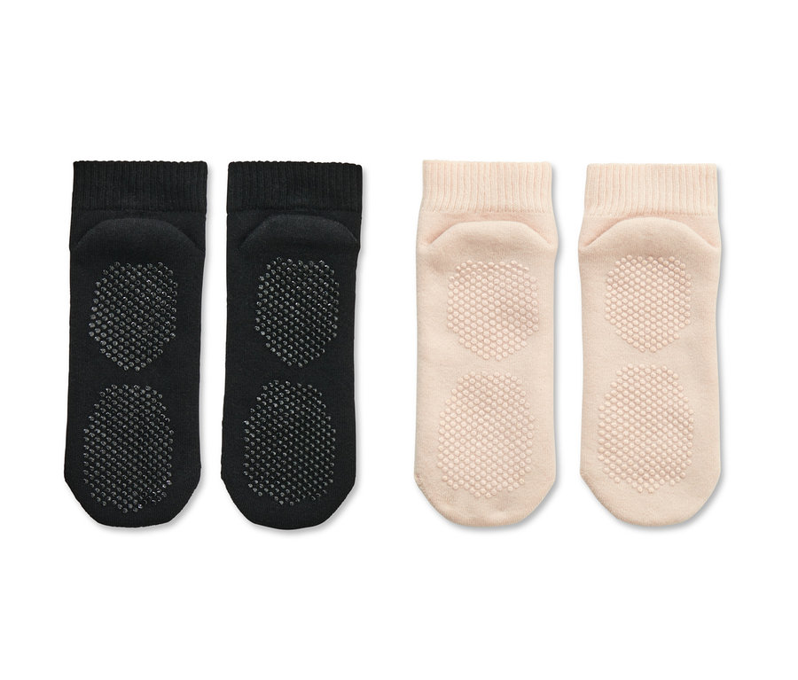 Dva páry ponožiek na jogu, čierne a béžové, ležia vedľa seba.