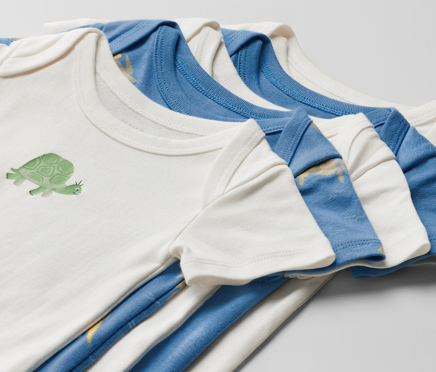 Detail piatich detských body s krátkymi rukávmi. Na jednom bielom body je obrázok korytnačky.