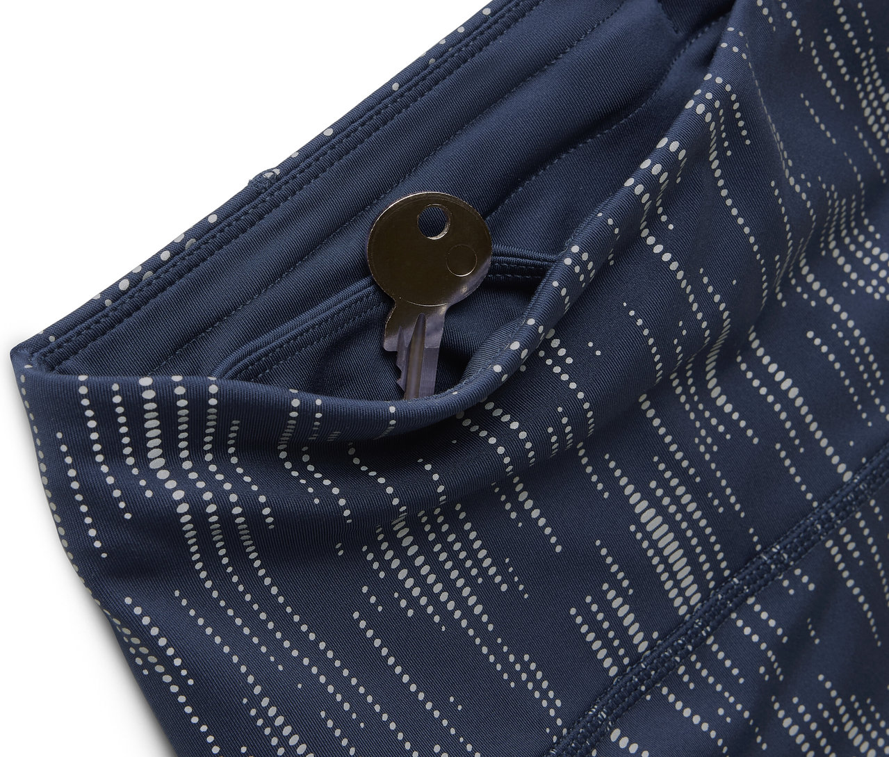 Detail modrých vzorovaných legín s kľúčom vo vrecku.