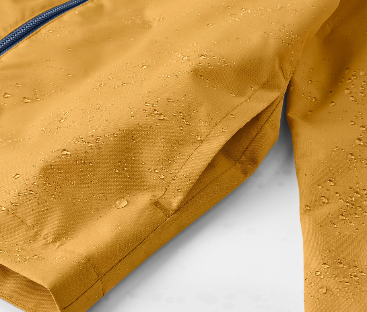 Detail žltej detskej bundy do dažďa s kvapkami vody.