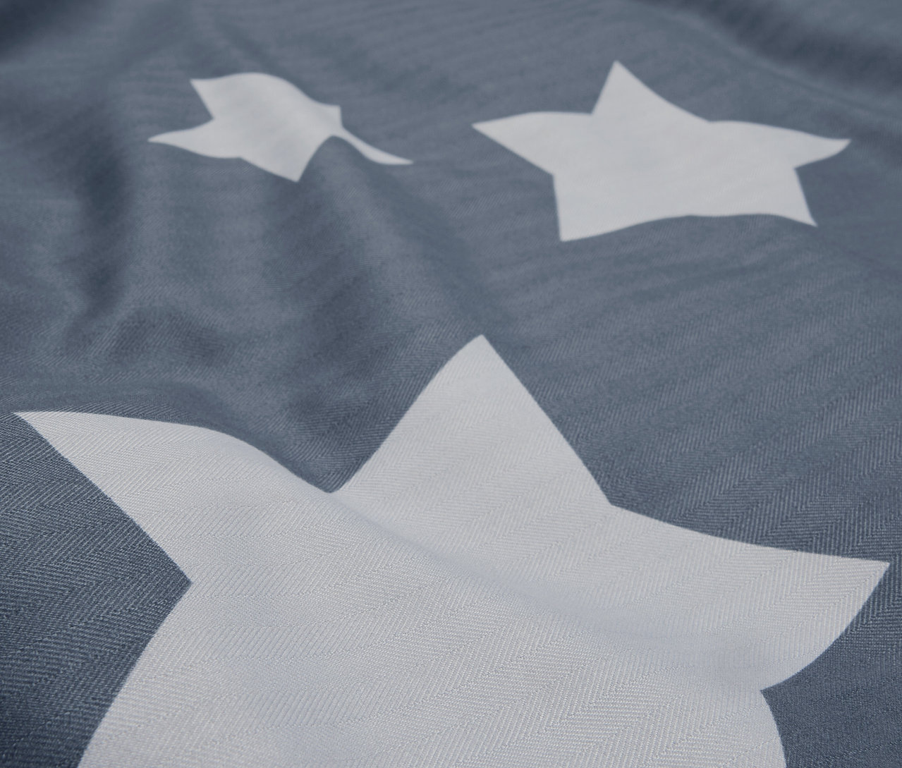 Detailný záber na sivú látku s bielymi hviezdami.