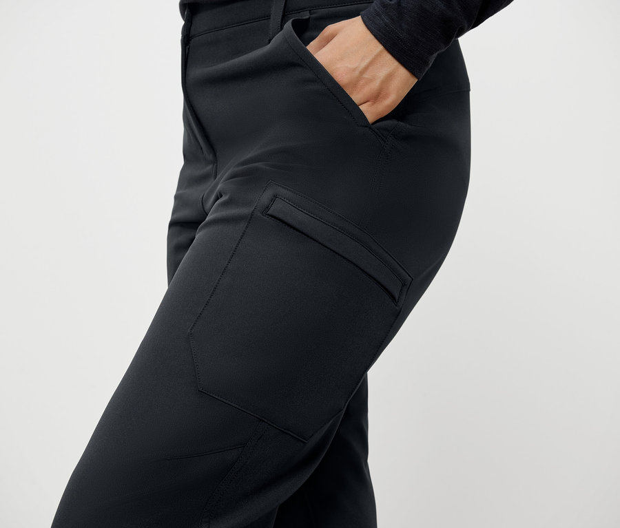 Detail ženy v čiernych nohaviciach s vreckami a rukou vo vrecku.