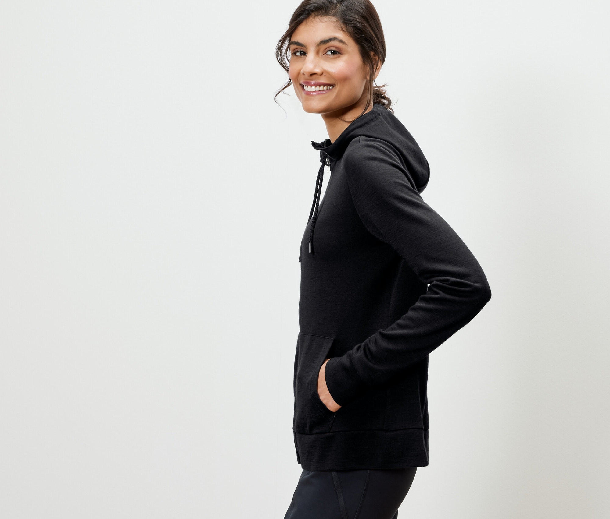 Žena pózuje v čiernej mikine s kapucňou s vlnou certifikovanou podľa RWS.