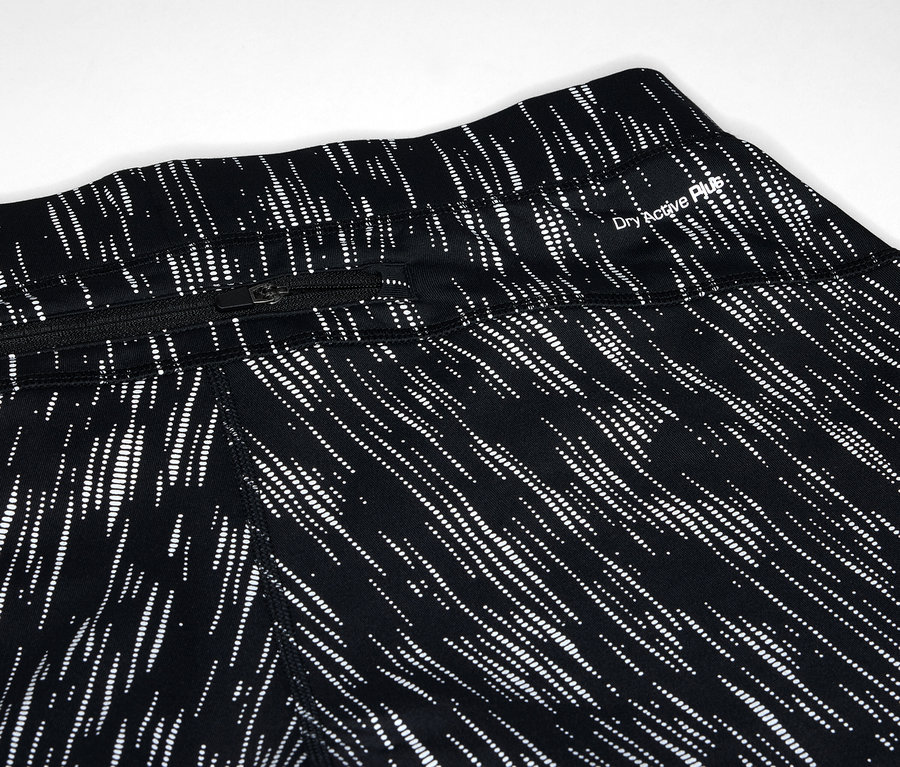 Detail čiernych legín so vzorom bielych čiar a vreckom na zips.