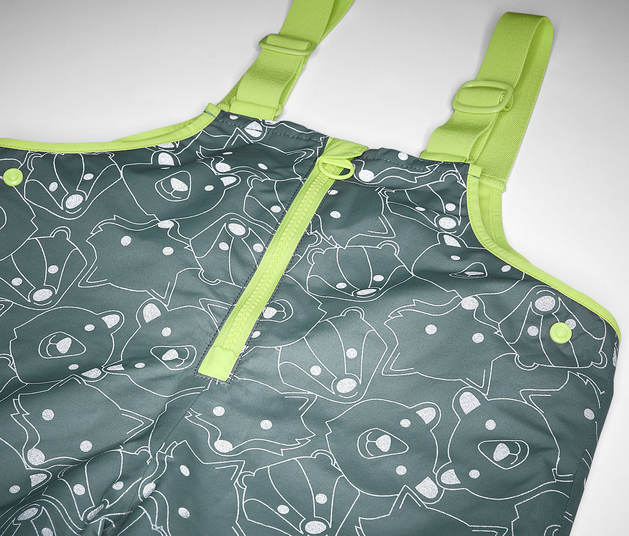 Detail detských termo nohavíc do dažďa s reflexnými prvkami, sivé s potlačou medveďov a líšok a žltými popruhmi.