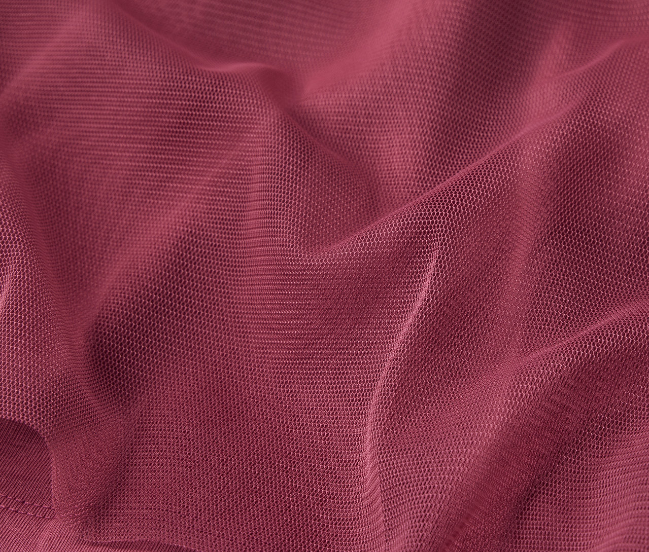 Detailný záber na vínovo červenú látku s jemnou textúrou a záhybmi.