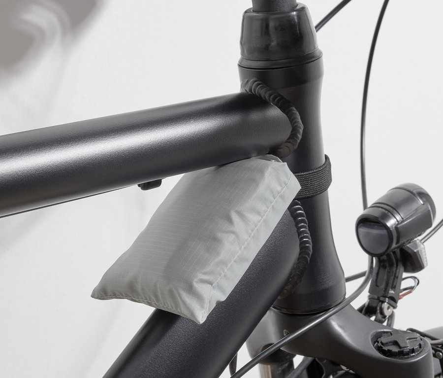 Sivá nákupná taška na bicykel pripevnená k rámu bicykla.