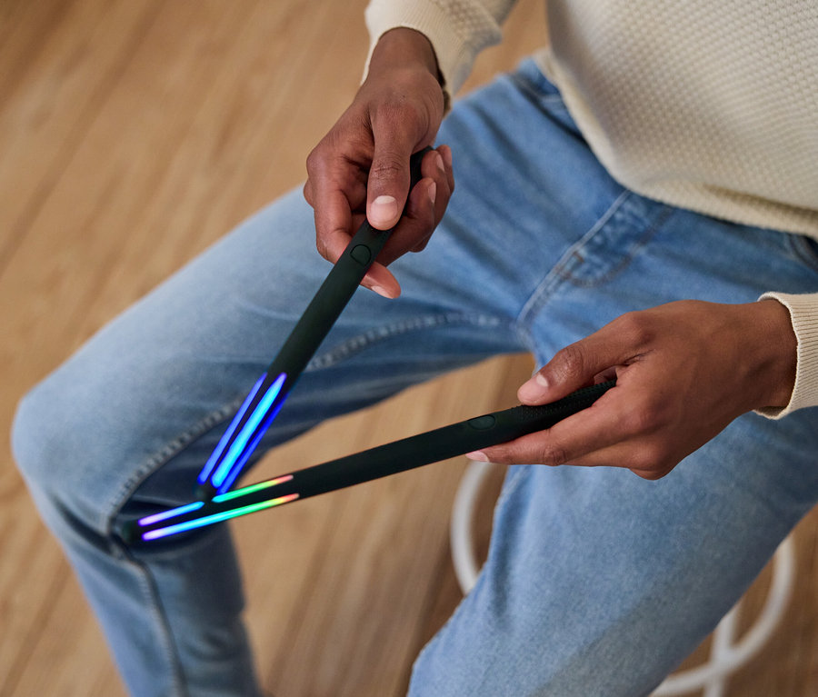 Muž drží dve čierne tyče so svetlami na koncoch.