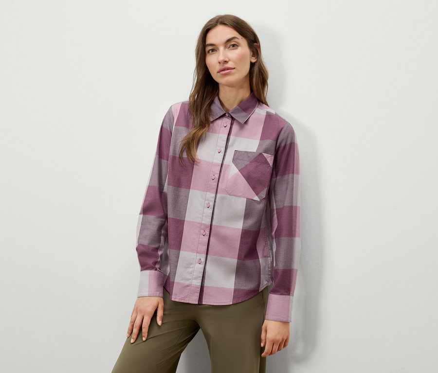 Žena pózuje v kockovanej košeli s dlhým rukávom a olivovozelených nohaviciach.