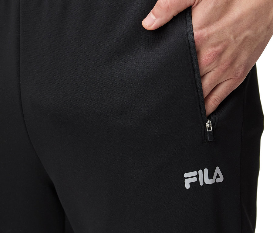 Muž si vkladá ruku do vrecka čiernych teplákov FILA.