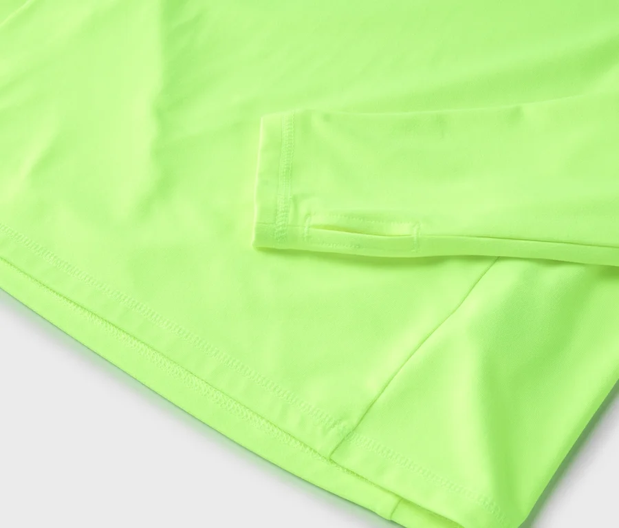 Detailný záber na svetlozelený top s dlhým rukávom a otvormi na palce.
