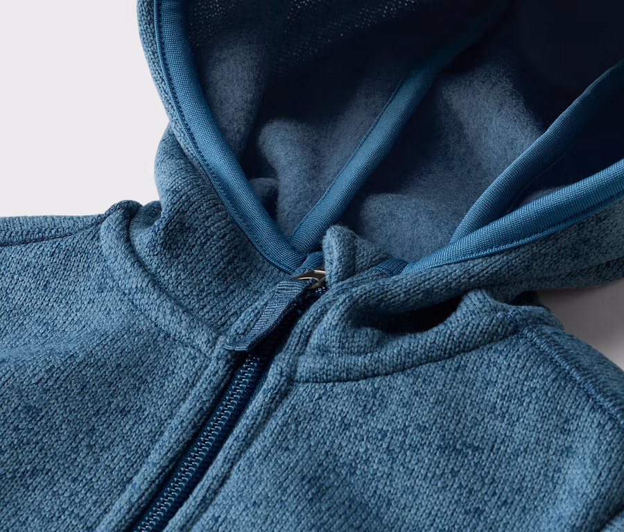 Detail modrozelenej fleecovej bundy s kapucňou a zipsom.