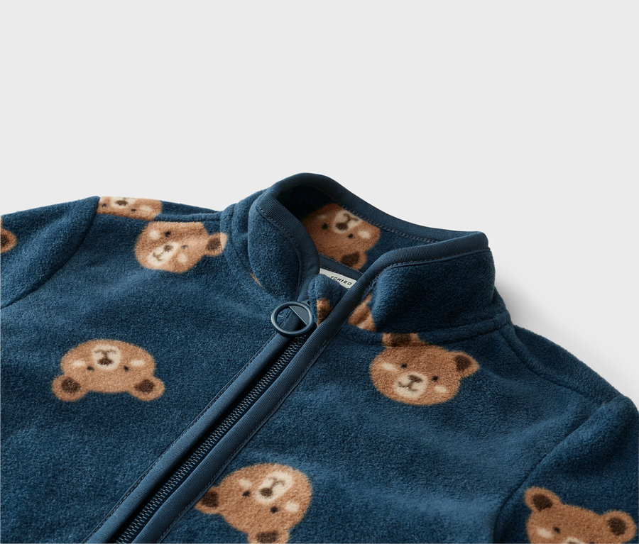 Detail modrej fleecovej bundy na zips s medvedíkmi.