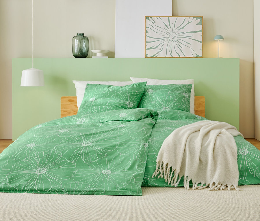 Posteľ so zelenou posteľnou bielizňou s bielym kvetinovým vzorom, bielou prikrývkou a svetlozeleným čelom.