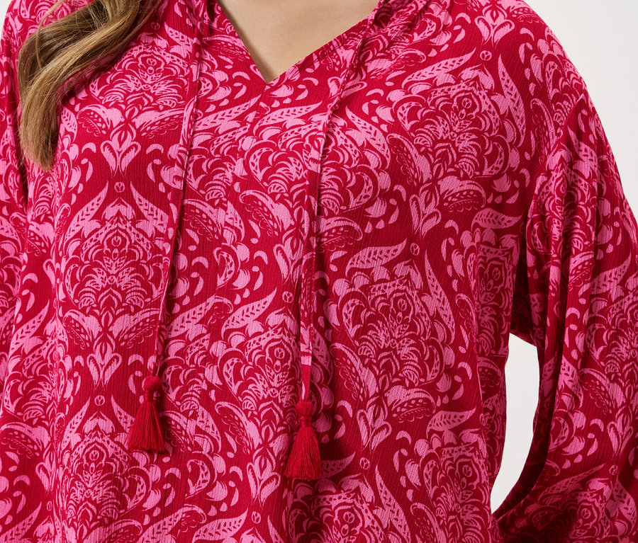 Detailný záber na červený top s ružovým kvetinovým vzorom a šnúrkou.