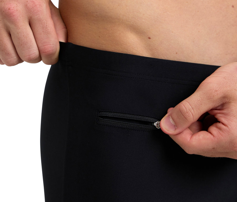 Muž si rozopína zips na čiernych nohaviciach.