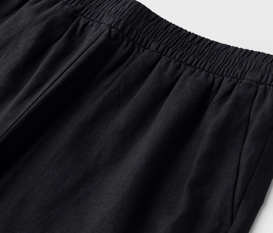 Detailný záber na pás čiernych nohavíc s elastickým pásom.