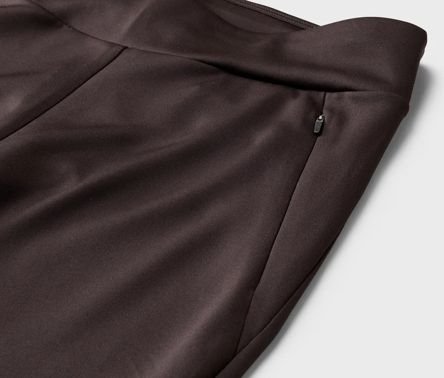 Detail hnedých nohavíc s vreckom na zips v páse.