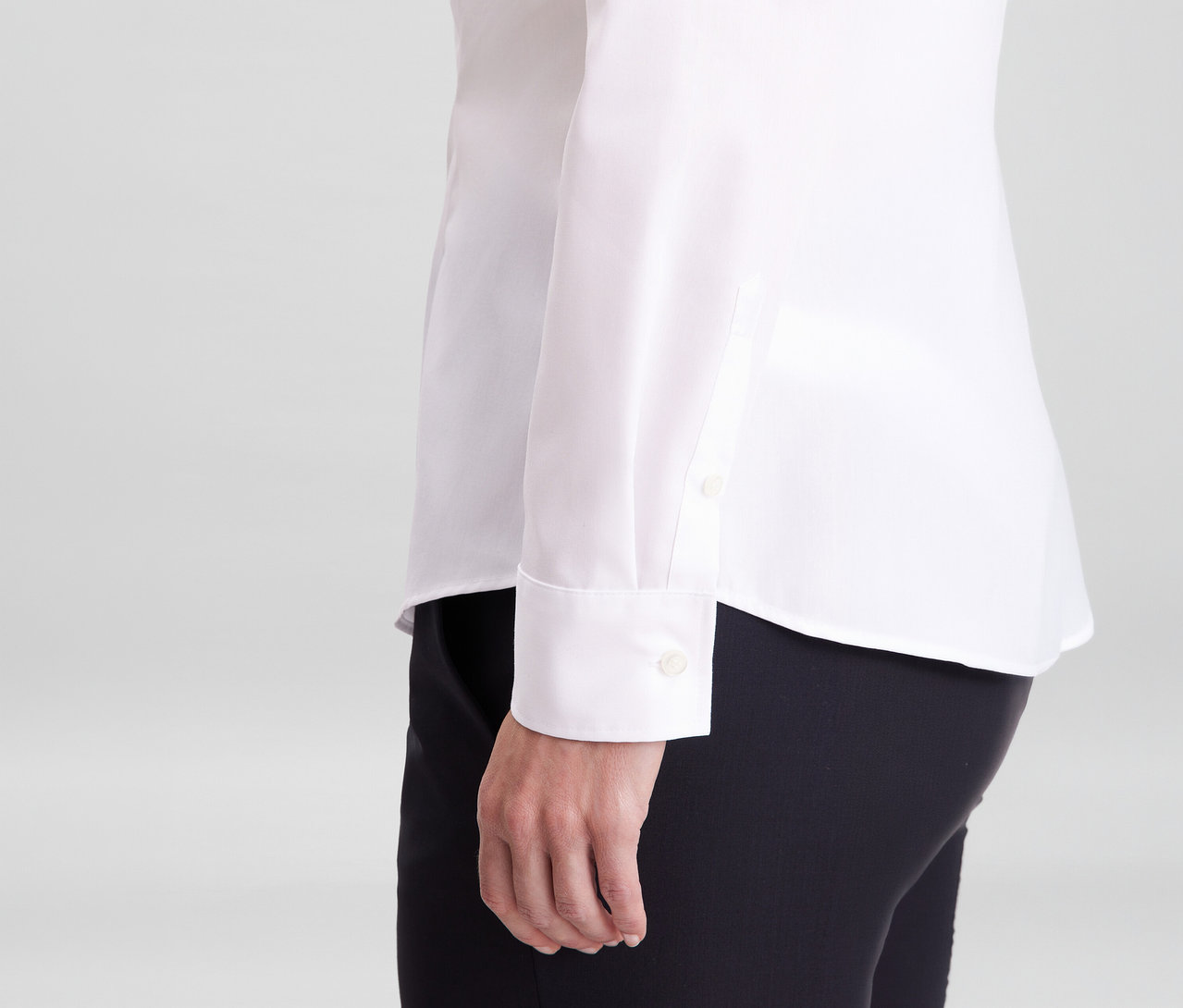 Osoba v bielej blúzke Seidensticker Slim Fit non iron a čiernych nohaviciach, viditeľný rukáv s manžetou.