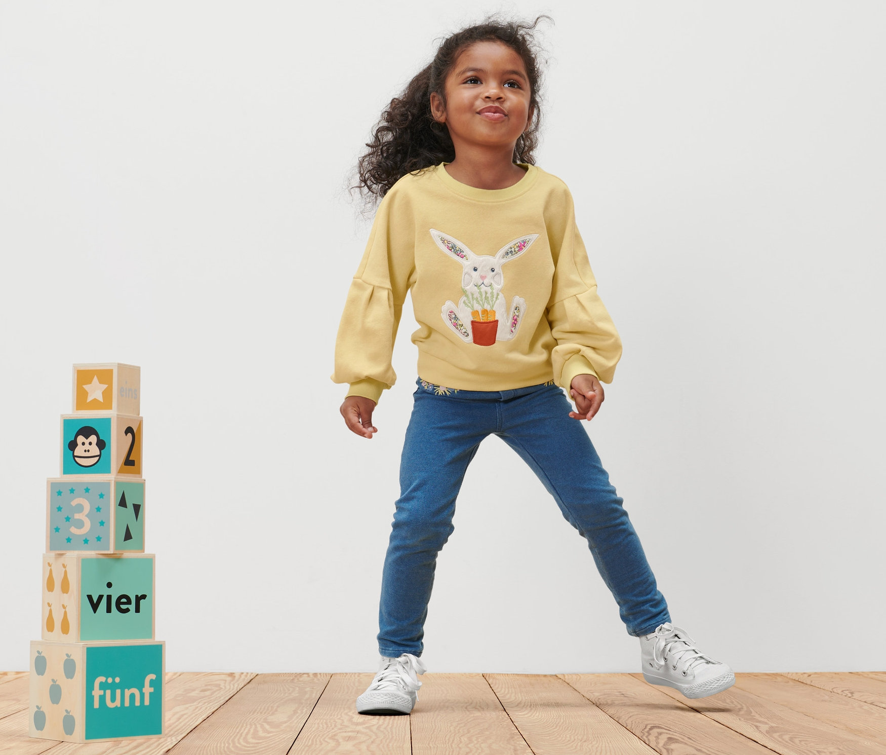 Dievčatko pózuje v detskej mikine s potlačou králika.