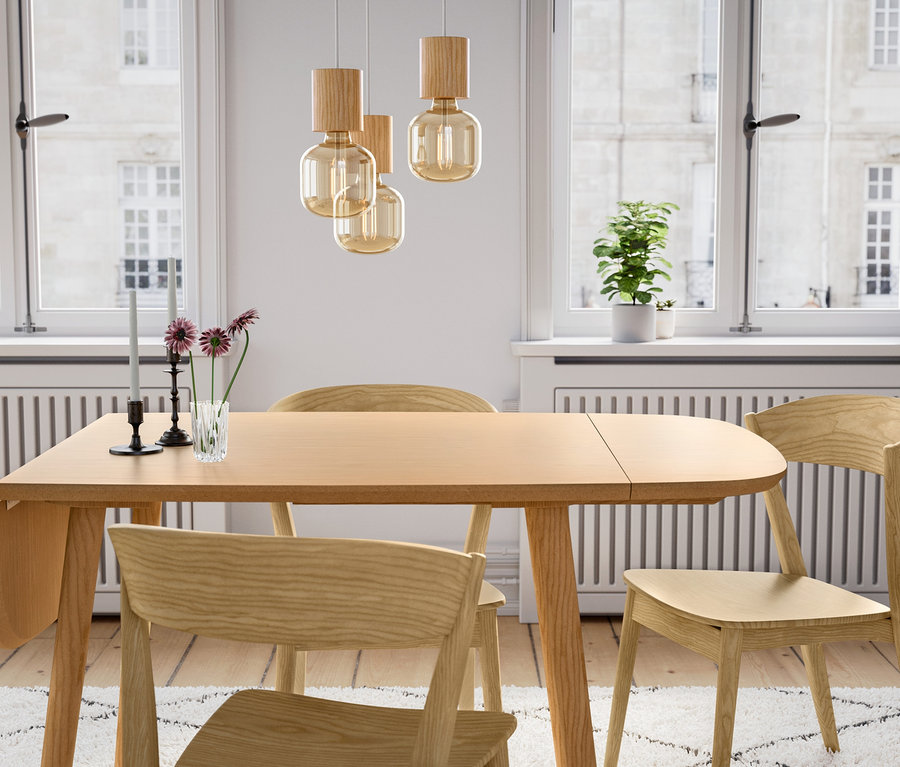 Drevený jedálenský stôl s tromi drevenými stoličkami a dreveným závesným svietidlom.