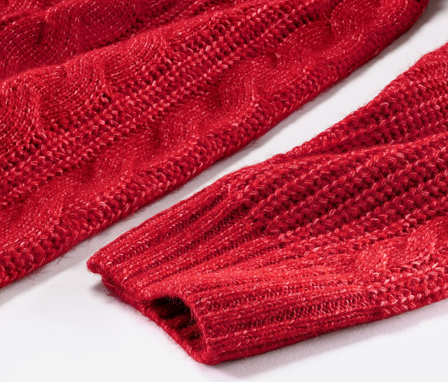 Detail červeného dlhého pleteného pulóvra s vrkočovým vzorom.