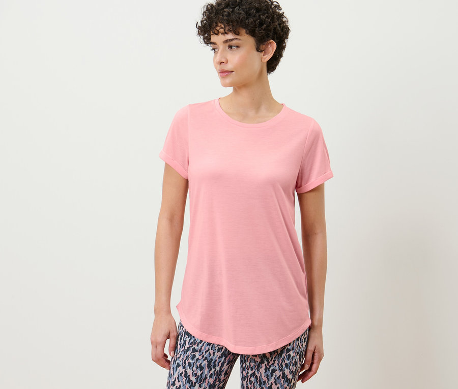 Žena pózuje v dlhom tričku fuksiové farby.