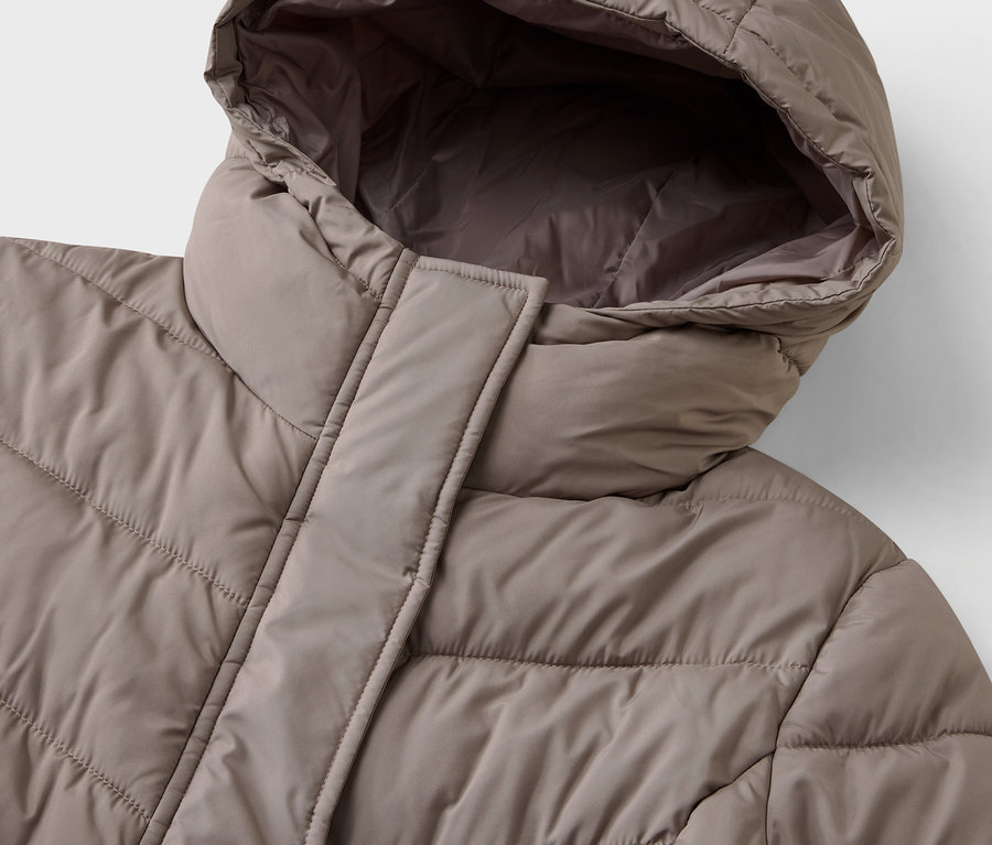 Detail béžovej prešívanej bundy s kapucňou.