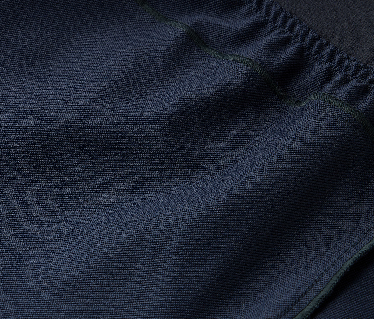 Detailný záber na textúru tmavomodrej látky so sťahovacou šnúrkou hore.