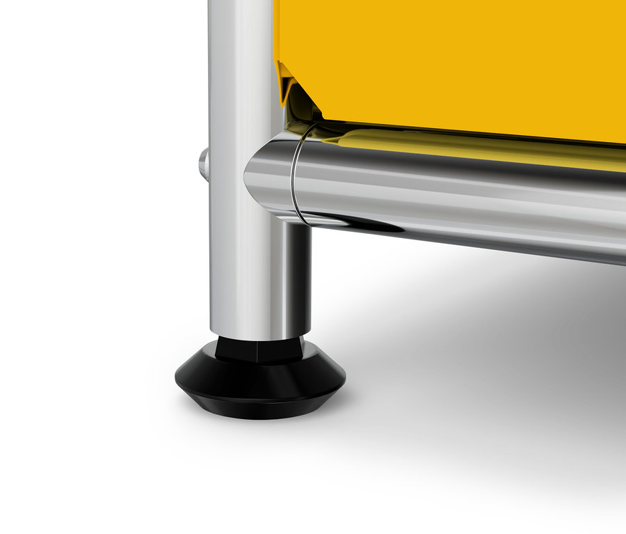 Detail žltého nábytku s chrómovanou nohou a čiernou pätkou.