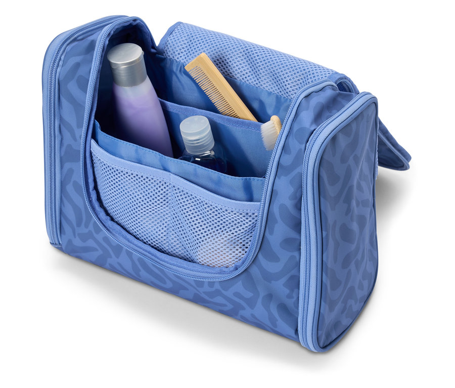 Otvorená svetlomodrá kozmetická taška s rôznymi cestovnými potrebami, ako sú šampón, hrebeň a zubná kefka.
