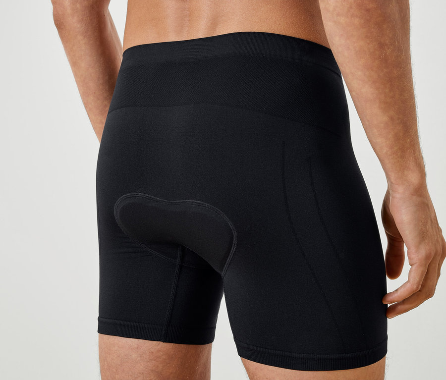 Detailný záber na chrbát muža v čiernych cyklistických šortkách.