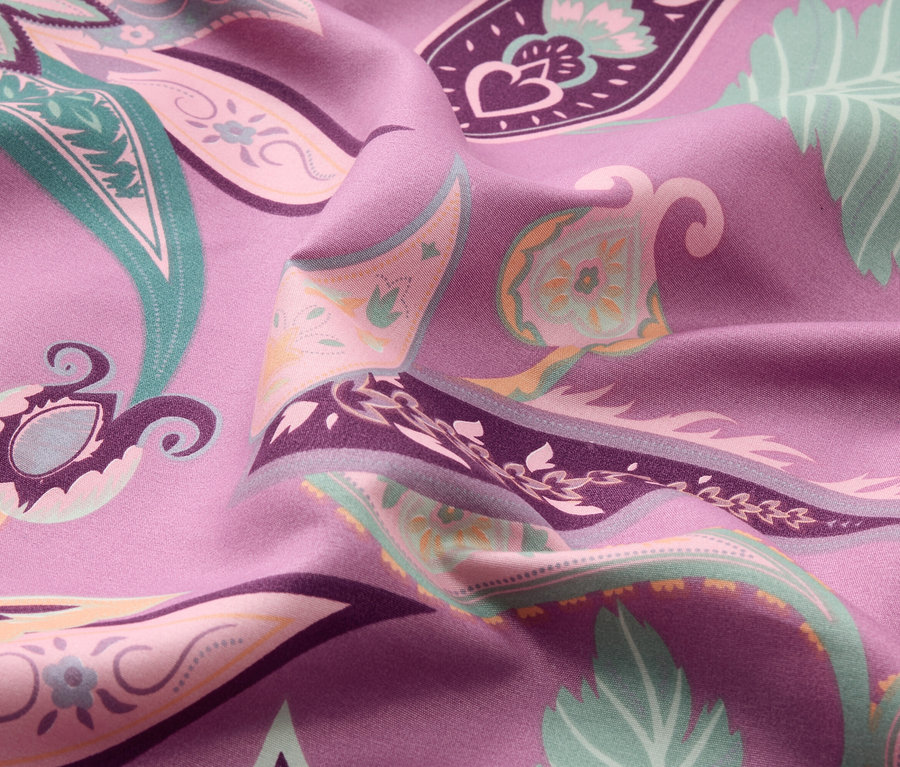 Detailný záber fialovej látky s farebným paisley vzorom.